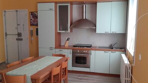 Une cuisine compacte comprenant une table à manger, des placards, une cuisinière et un four à micro-ondes.