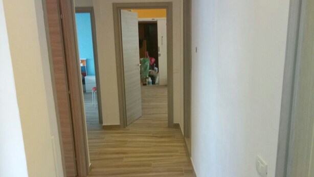 Un couloir avec un plancher en bois et des murs blancs.