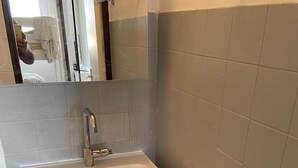 Une salle de bain avec un lavabo blanc, un miroir et un porte-serviettes.