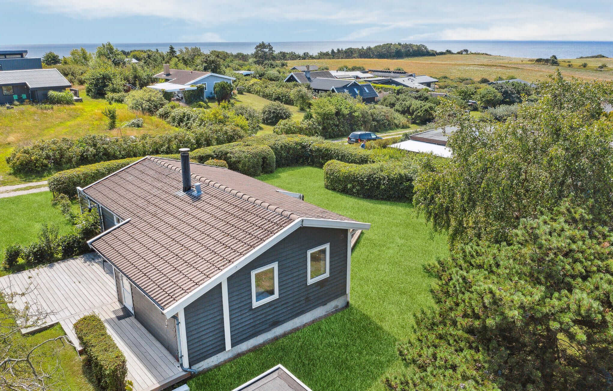 A residential area with houses, a grassy yard, and a view of the sea.