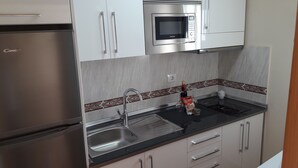 Una cocina moderna con microondas integrado, pileta de acero inoxidable y refrigerador.