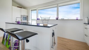 Een moderne keuken met een bar, grote ramen en een minimalistisch design.