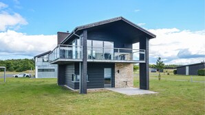 Een modern huis met twee verdiepingen, een balkon, een garage en een klein terras.