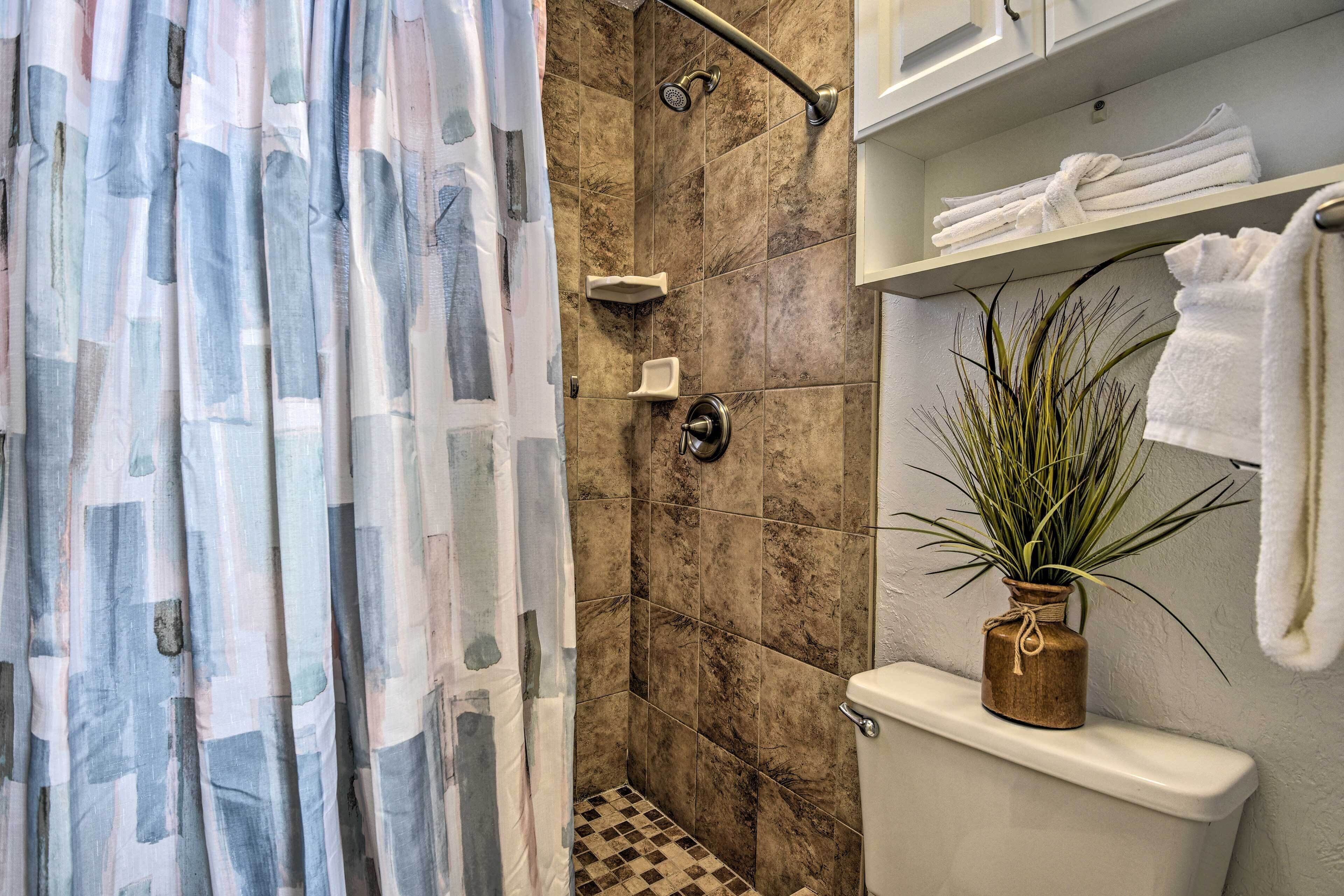 Een badkamer met een douche, toilet, handdoekrek en een plant in pot.
