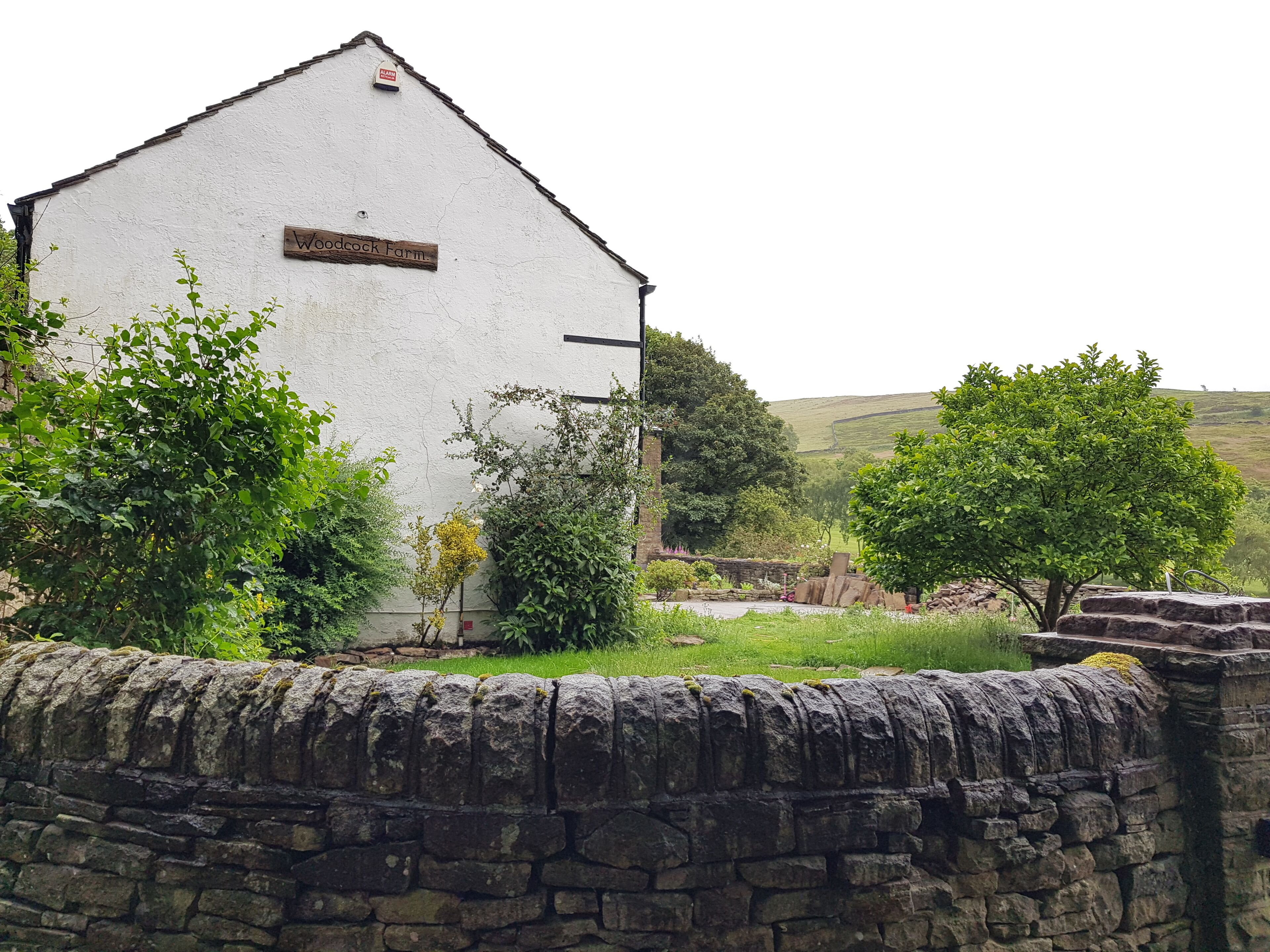 En vit byggnad med en skylt som visar texten ”Woodrock Farm”.
