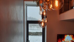 Et moderne interiør med pejs, et fjernsyn og udsigt til et snelandskab gennem en glasdør.