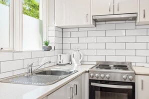 Una cocina moderna con armarios blancos, un fregadero de acero inoxidable, una estufa y un tostador.