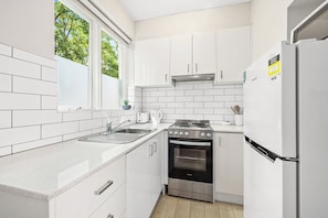 A modern kitchen with white cabinetry, a stainless steel stove, and a built-in oven.
