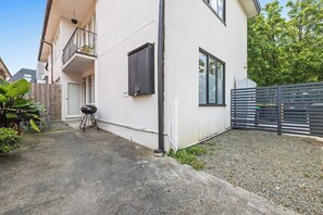 A residential building with a balcony, a barbecue grill, and a gated area.