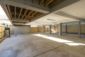 An empty garage with a concrete floor, wooden beams, and a closed garage door.