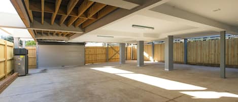 An open garage with a concrete floor, wooden beams, and a closed garage door.
