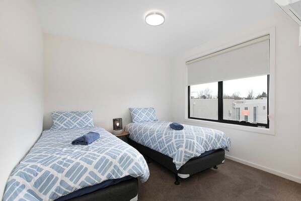 A bedroom with two beds, a window with a view, and a ceiling light.
