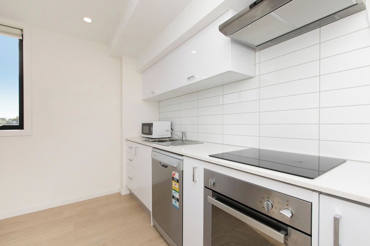 Een moderne keuken met witte kasten, een magnetron, een vaatwasser en een inbouwoven.