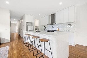 Una cocina moderna con una isla central, taburetes de bar y un salpicadero de azulejos.