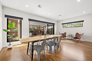 Un comedor con una mesa de madera y sillas metálicas, una alfombra pequeña y una ventana con vistas a zonas verdes.