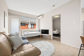 A modern living room with a leather sofa, a flat-screen TV, and a round rug.