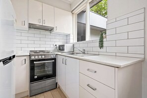 A compact kitchen with white cabinetry, a built-in oven, and a microwave.