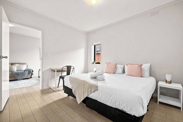 A modern bedroom with a large bed, bedside tables, a desk, and a chair.