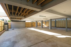 An open garage space with concrete flooring, wooden beams, and a closed garage door.