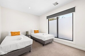 A bedroom with two beds, a large window, and a ceiling vent. - Domi Rentals - The Rayhur Residence (Clayton South)