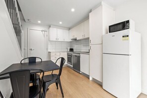 A modern kitchen with white cabinetry, a black dining table, and a built-in microwave.