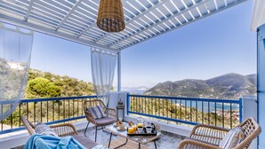 A balcony with wicker furniture, a table with breakfast items, and a scenic view of the landscape. - Villa Avaton Magnificent sea view and Skopelos town (Skopelos)
