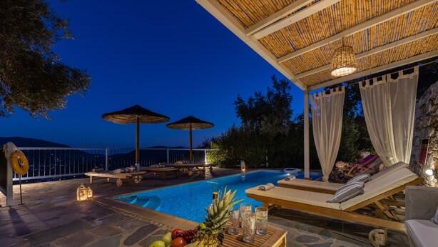 A poolside area with lounge chairs, umbrellas, and a fruit bowl. - Villa Avaton Magnificent sea view and Skopelos town (Skopelos)