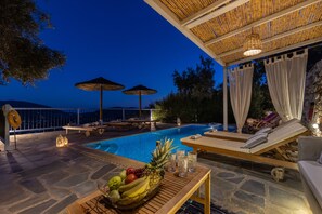 A poolside area with lounge chairs, umbrellas, and a fruit bowl. - Villa Avaton Magnificent sea view and Skopelos town (Skopelos)