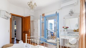 A bedroom with a bed, a desk, and a chair. There is a door leading to another room. - Villa Avaton Magnificent sea view and Skopelos town (Skopelos)