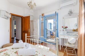 Un dormitorio con cama, escritorio, silla y baño visible a través de una puerta abierta.