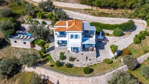 A two-story house with a stone facade, a tiled roof, and a paved patio area with outdoor seating. - Villa Avaton Magnificent sea view and Skopelos town (Skopelos)