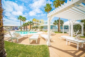 Un espace piscine avec des chaises longues et une pergola.