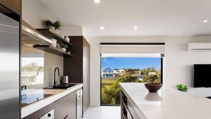 A modern kitchen with a view of the sea, built-in appliances, and a large window. - Luxurious Home Close to The Beach (Surf Beach)