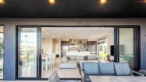 A modern interior with a dining area, a sofa, and a kitchen in the background.