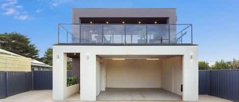 A modern two-story building with a covered garage entrance and a balcony.