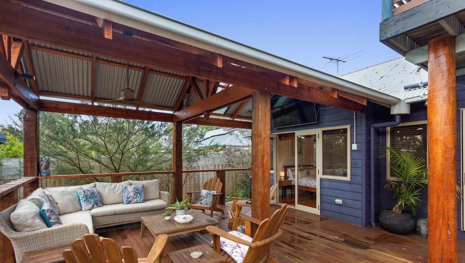 Eine überdachte Terrasse mit einer Couch, Stühlen und einem Tisch.