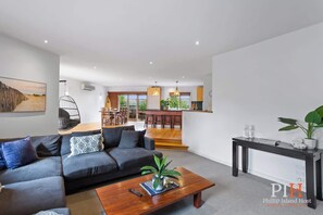 A modern living room with a grey sofa, a wooden coffee table, and a dining area with wooden chairs. - Beachwood Retreat for Ultimate Relaxation (Cowes)