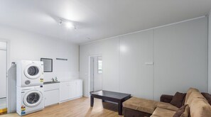 Un appartamento moderno con lavatrice, tavolo da pranzo e divano.