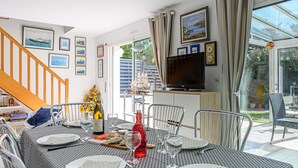 Ein Essbereich mit Tisch für vier Personen, einem Fernseher und einer Treppe, die zu einer weiteren Ebene führt.