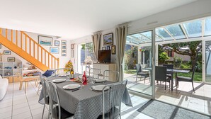Ein geräumiges Wohnzimmer mit Essbereich, einer Treppe und einer großen Glasdoor, die zu einem Garten führt.