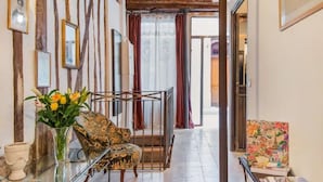 A hallway with a patterned armchair, a glass vase with flowers, and a painting on a small table. - Romantic, air-conditioned apartment in Paris in the heart of the historic Marais district (Paris)