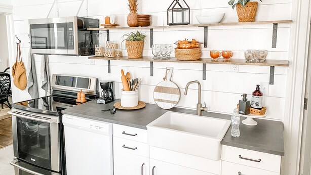 A modern kitchen with white cabinetry, stainless steel appliances, and decorative items on shelves. - Modern Farmhouse Suite at The Dorley (Sandusky)