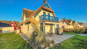 Ein traditionelles Haus mit steilem Satteldach, einem Balkon und einem Strohdach.