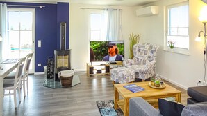 Ein Wohnzimmer mit Fernseher, Sofa, Couchtisch und Kamin.