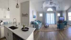 A modern kitchen with white cabinets, a sink, and a dining area with a wooden table and chairs.