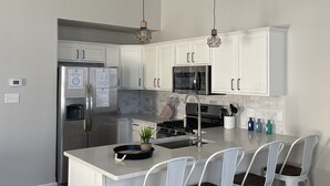 A modern kitchen with white cabinetry, stainless steel appliances, and a central island with bar stools.