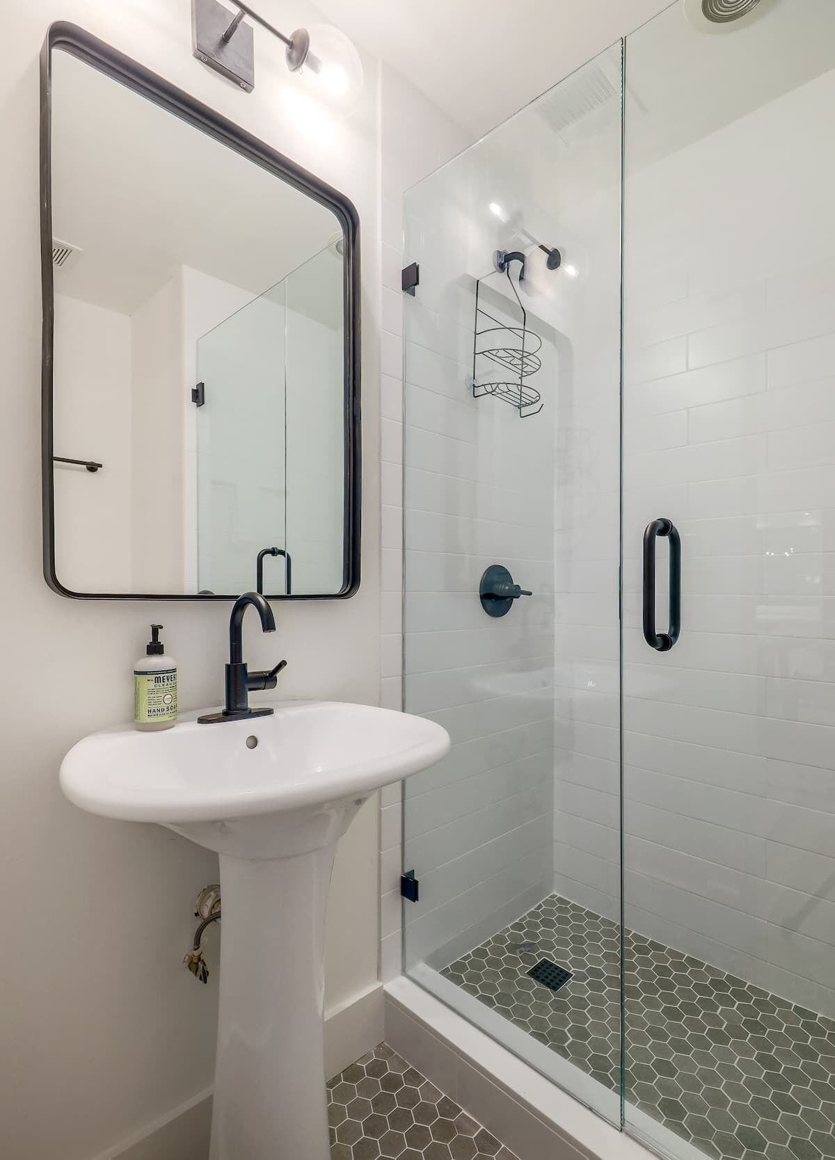 A bathroom with a white sink, a mirror, and a glass shower enclosure.