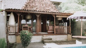 A traditional house with a tiled roof, a porch with wooden railings, a small garden, and a swimming pool. - Natural View Sidemen Cottage (Sidemen)