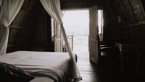 A bedroom with a bed, a nightstand, and a window with curtains. - Natural View Sidemen Cottage (Sidemen)