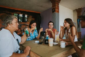 A group of people sitting around a wooden table in a room with brick walls and a checkered pattern on the wall. - Natural View Sidemen Cottage (Sidemen)